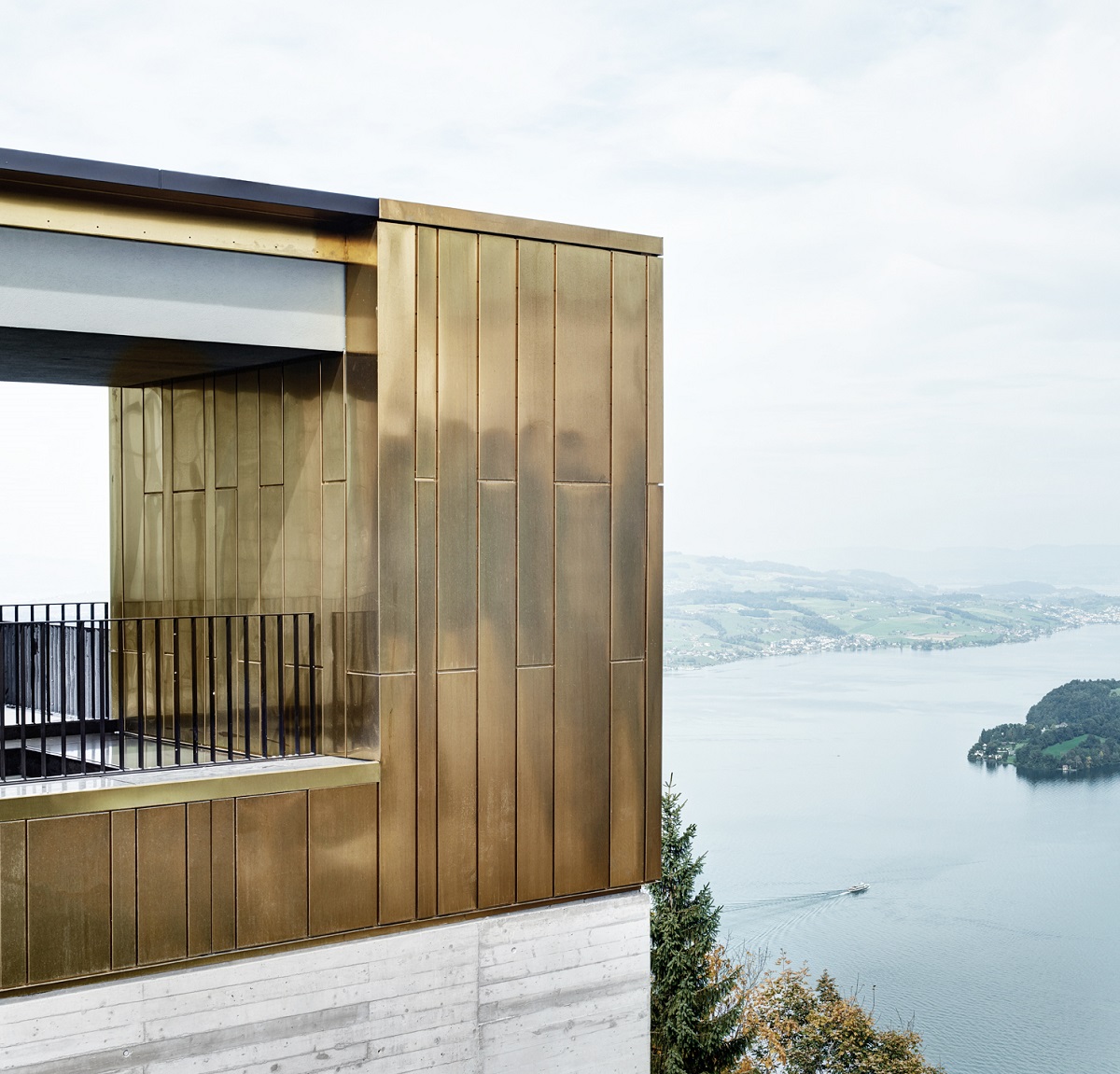 Top floor of the Hotel Bürgenstock. Topmost part of the building is made from cassettes of Nordic Brass copper. The part of the building below it, is made from concrete. Green hills and Lake Lucerne can be seen in background.